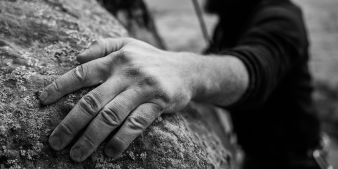 Hand grasping rock while rock climbing