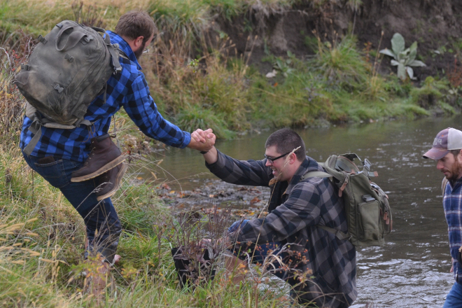 Two men using teamwork to climb out of a river bank