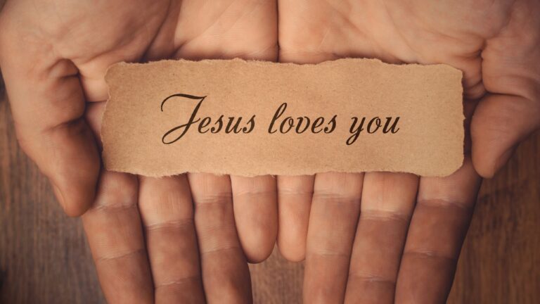 Hands held out holding paper that says Jesus Loves You.